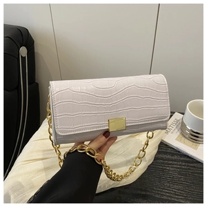 Close-up of white croc-embossed texture with gold chain and square buckle detail
