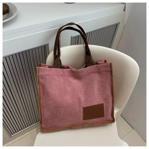 Detail der rosa Cord-Tragetasche mit vertikaler Textur und braunem Mode-Etikett