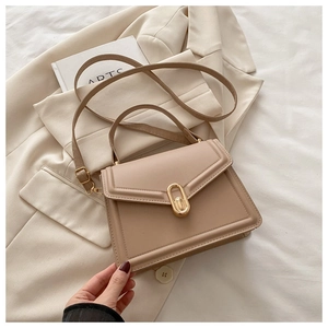 Détail d'un sac à main beige en similicuir avec un fermoir rotatif ovale en métal doré
