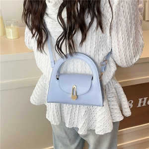 Minimalist light blue leather crossbody bag with vintage gold buckle closure shown on model