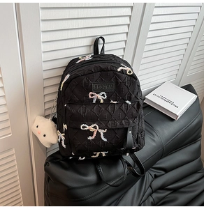 Detail of black quilted backpack with butterfly embroidery and plush cloud charm