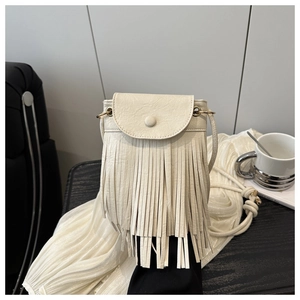 Détail d'un sac bandoulière crème avec franges, boucle ronde et texture grainée