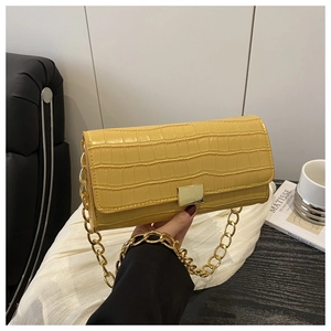 Detailed shot of yellow crocodile texture leather bag with a bold gold chain handle