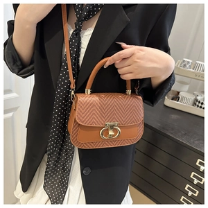 Détail du sac à main marron tissé avec boucle métallique dorée et bandoulière en cuir