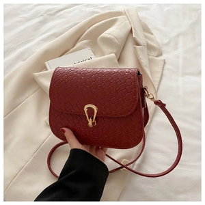 Dettaglio della borsa a sella in pelle intrecciata bordeaux con fibbia dorata