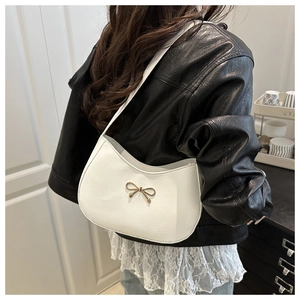 Detailed view of white crescent shoulder bag with golden bow hardware on smooth PU leather
