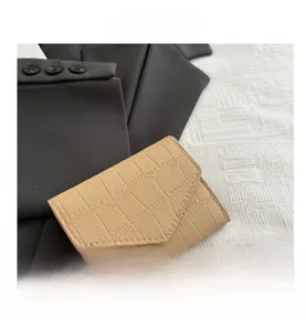Dettaglio del portafoglio beige con trama a coccodrillo e cuciture precise su tessuto