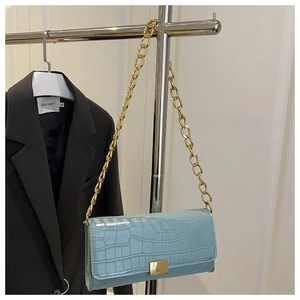 Close-up of light blue handbag with crocodile texture and gold chain link strap