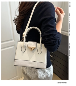 Detail of white crocodile pattern patchwork handbag with golden turn-lock and chain strap