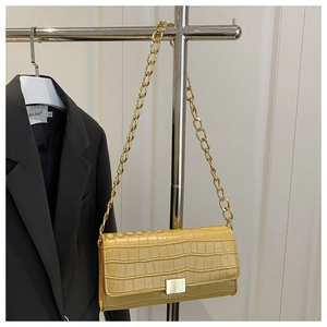 Detailed view of yellow faux leather flap bag with crocodile texture and gold chain strap