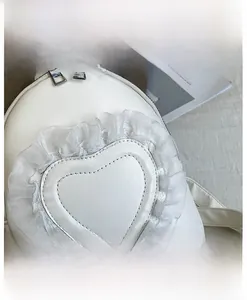 Detail of white PU leather backpack featuring heart stitching and translucent mesh ruffles