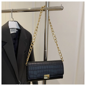 Detail of black crocodile texture faux leather bag with golden chain and metal lock