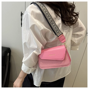Detail of pink patchwork crossbody bag with textured fabric strap and gold hardware