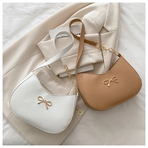 Detail of hobo shoulder bags with golden bow hardware on white and camel faux leather
