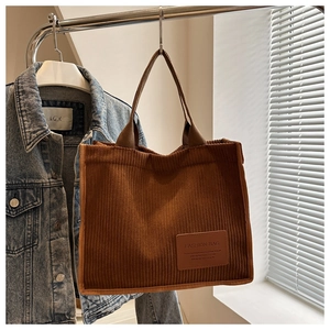 Detail einer braunen Cord-Tragetasche mit dicker Textur und einem dekorativen Leder-Patch