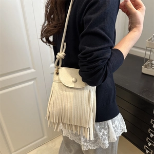 Sac bandoulière crème chic avec franges et bandoulière nouée porté par un mannequin