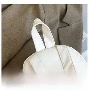 Detail display of a white matte leather backpack with a wide handle and silver metal buckles