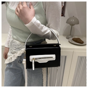 Piccola borsa quadrata a contrasto bianco e nero mostrata in un ambiente interno elegante