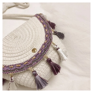 Détail du sac bandoulière blanc tissé avec des pompons violets et une boucle dorée