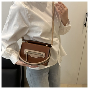 Dettaglio di una borsa a tracolla bicolore marrone e beige con cerniera decorativa