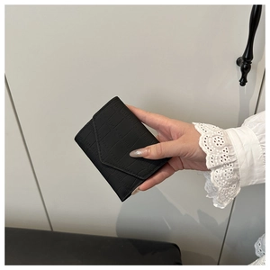 Dettaglio del portafoglio nero con trama a coccodrillo e patta triangolare alla moda