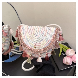Détail du sac en paille tissé coloré avec des franges roses et un fermoir à boucle dorée
