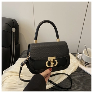 Détail d'un sac à main en cuir noir avec un fermoir rotatif métallique doré caractéristique