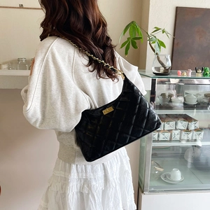Borsa tote trapuntata in pelle nera con catena dorata indossata da modella in ambiente minimal