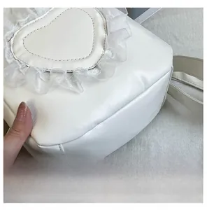 Detailed close-up of white heart-shaped PU leather bag with delicate lace trim edges