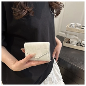Dettaglio di un mini porta carte bianco con trama a coccodrillo a forma di bustina