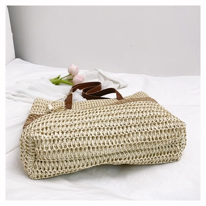 Detail of large straw tote bag with brown woven stripes and slim shoulder straps