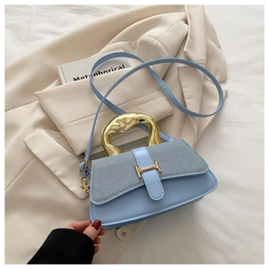 Detail view of light blue handbag with metallic handle on a beige blazer background