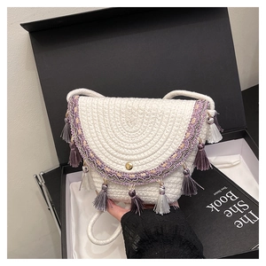 Détails du tissage sur un sac selle blanc avec broderie ethnique et pompons colorés