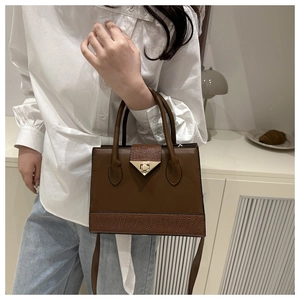 Detail of vintage brown leather handbag with animal texture and gold clasp on a model