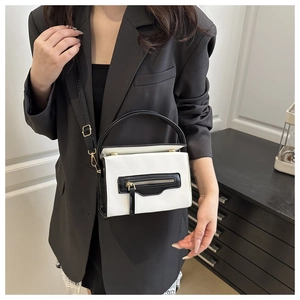 Dettaglio della piccola borsa quadrata a contrasto bianco e nero con zip e finiture dorate