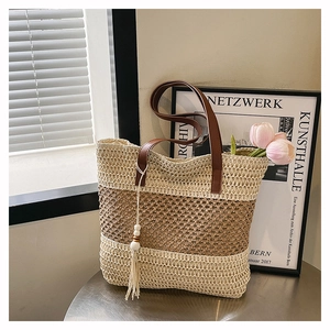 Detail of woven beach tote showing color-block straw texture and leather handles
