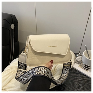 Detail of elegant beige patchwork crossbody bag with textured fabric and wide geometric strap