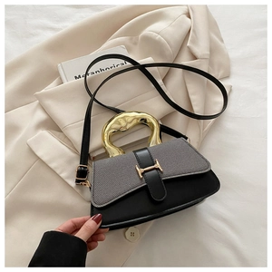 Detail of grey textured fabric and black leather bag with gold H-buckle and metal handle