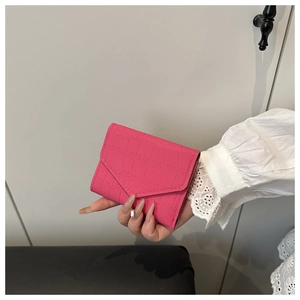 Dettaglio del portafoglio a busta rosa con elegante trama in pelle a coccodrillo