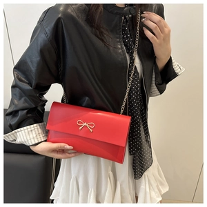 Detail of red envelope crossbody bag with gold bow knot and metal chain strap