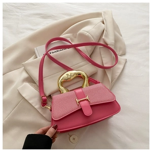 Detail view of pink crossbody bag with unique gold metal handle and H-shaped buckle