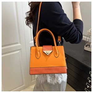 Detail of orange patchwork satchel with golden hardware and textured flap on model