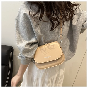 Detail of minimalist beige PU leather crossbody bag featuring adjustable silver buckle strap