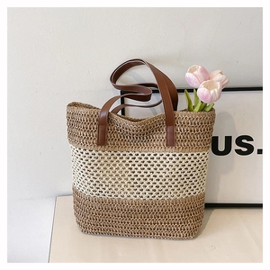 Detail of three-tone woven straw tote bag with brown leather handles and hollow patterns