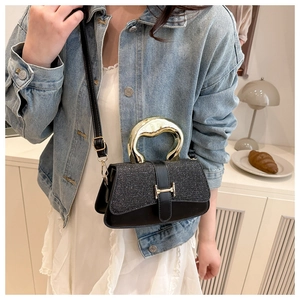 Black mini crossbody bag with gold metal top handle and sparkling glitter flap detail