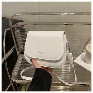 Detail of white faux leather crossbody bag featuring Fashion Trend lettering and silver hardware