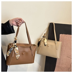 Detail of elegant tote bags with decorative silk scarves in brown and beige colors
