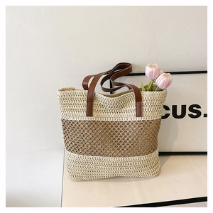 Detailed close-up of color-block straw tote bag with brown leather handles and hollow weave