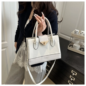 Detailed side view of a white handbag with animal pattern texture and gold hardware
