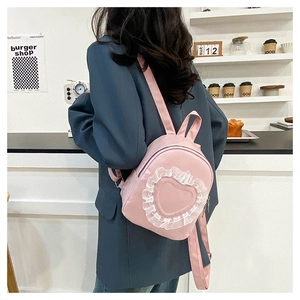 Detail of pink backpack featuring white lace heart patches and adjustable shoulder straps